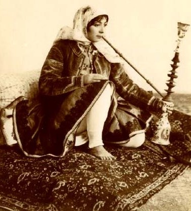 foto antigua de mujer con traje típico marroquí fumando en una shisha