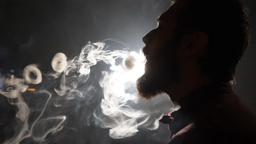 hombre haciendo aros de humo
